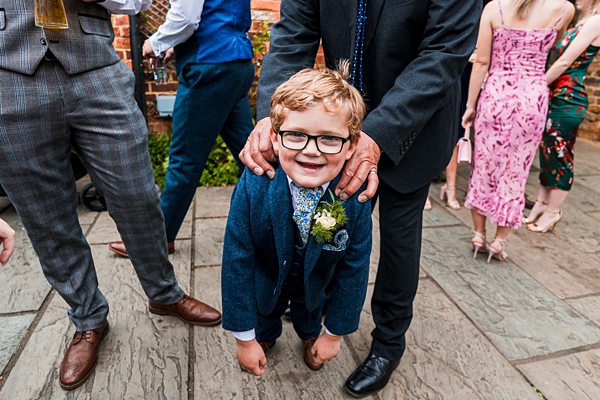 Smiling child in suit at lively outdoor gathering.