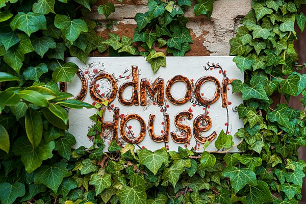 Sign 'Dodmoor House' covered in green ivy.