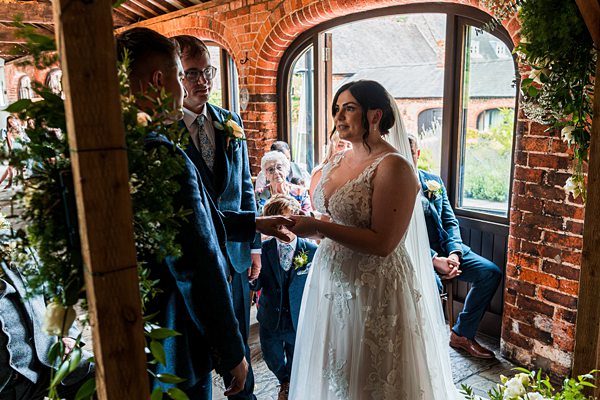 Bride and groom exchanging vows in rustic venue.