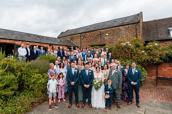 Large wedding group outside rustic barn venue