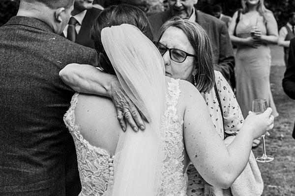 Emotional wedding embrace with champagne and guests.