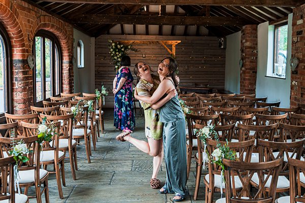 Two women hugging in decorated wedding venue.