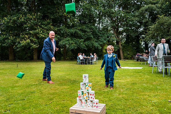 Man and boy play garden tin can toss game.