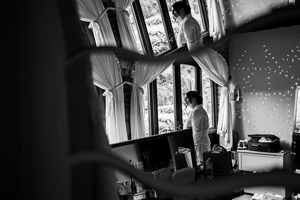 Man in suit gazing out a window, reflection visible.
