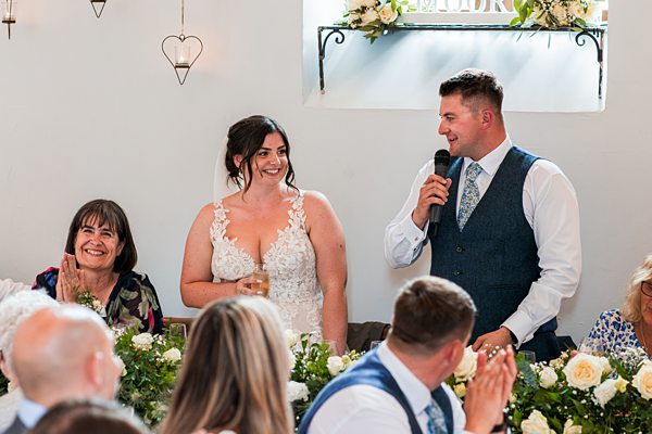 Bride and groom speaking at wedding reception.