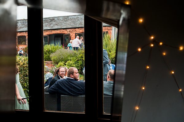 People at outdoor gathering viewed through window.