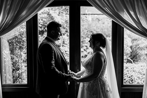 Bride and groom holding hands by window