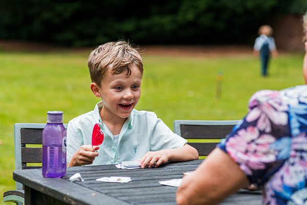 Boy playing cards outside with smiling elder.