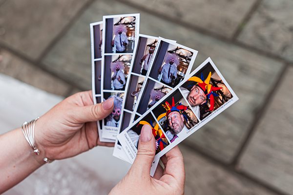 Person holding photo booth strips outdoors