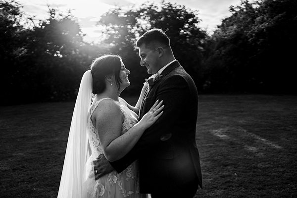 Bride and groom embracing at sunset wedding.