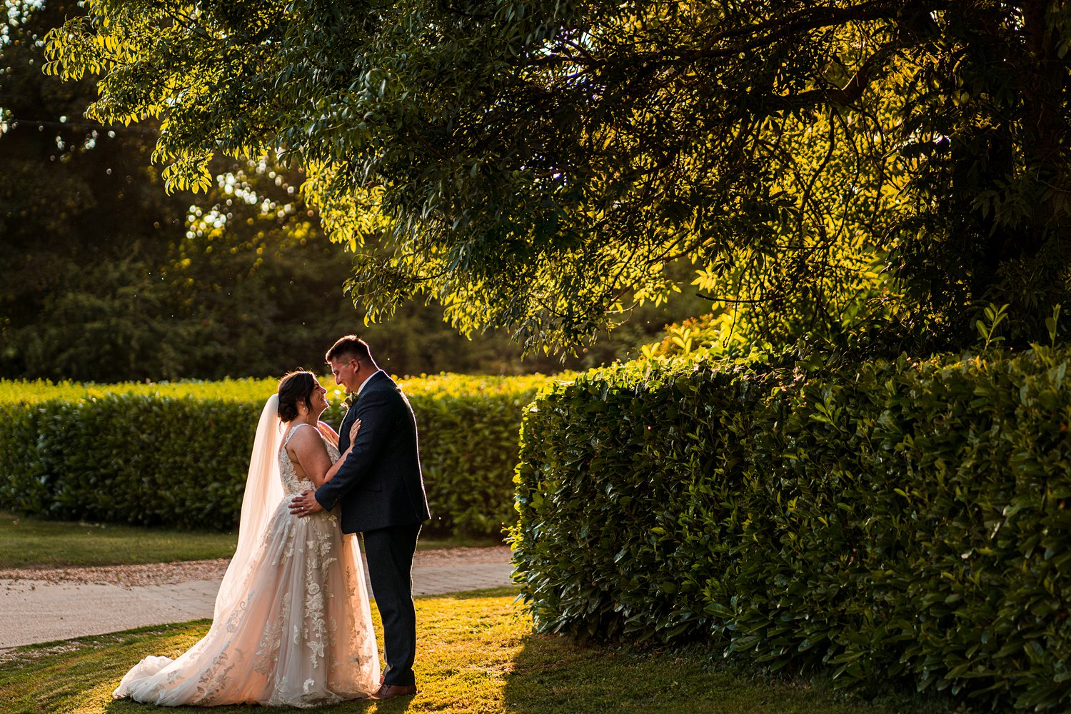Couple embracing in sunlit garden setting.