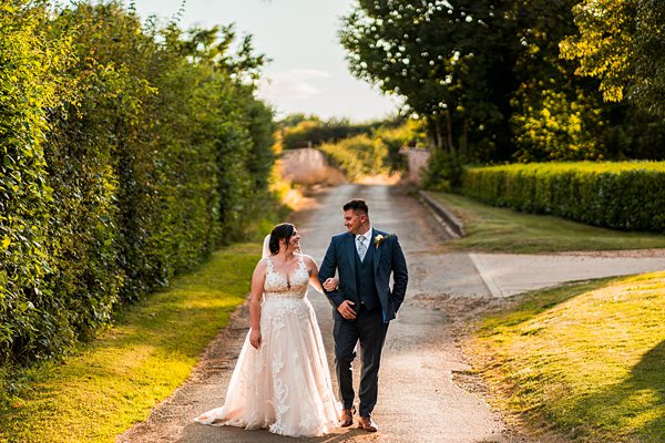 Bride and groom walking on sunny path