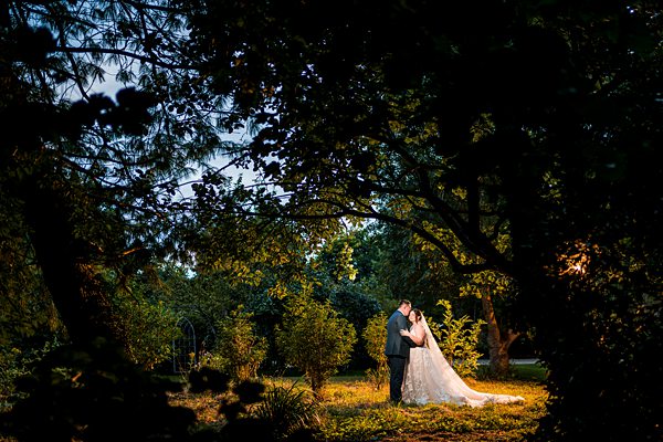 Bride and groom kissing in forest clearing.