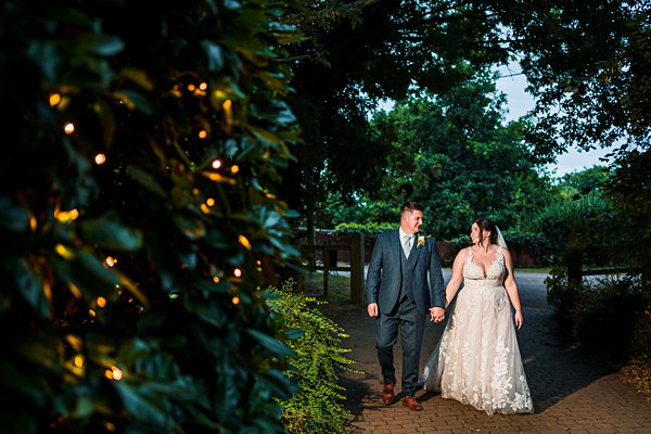 Bride and groom walking hand in hand outdoors.