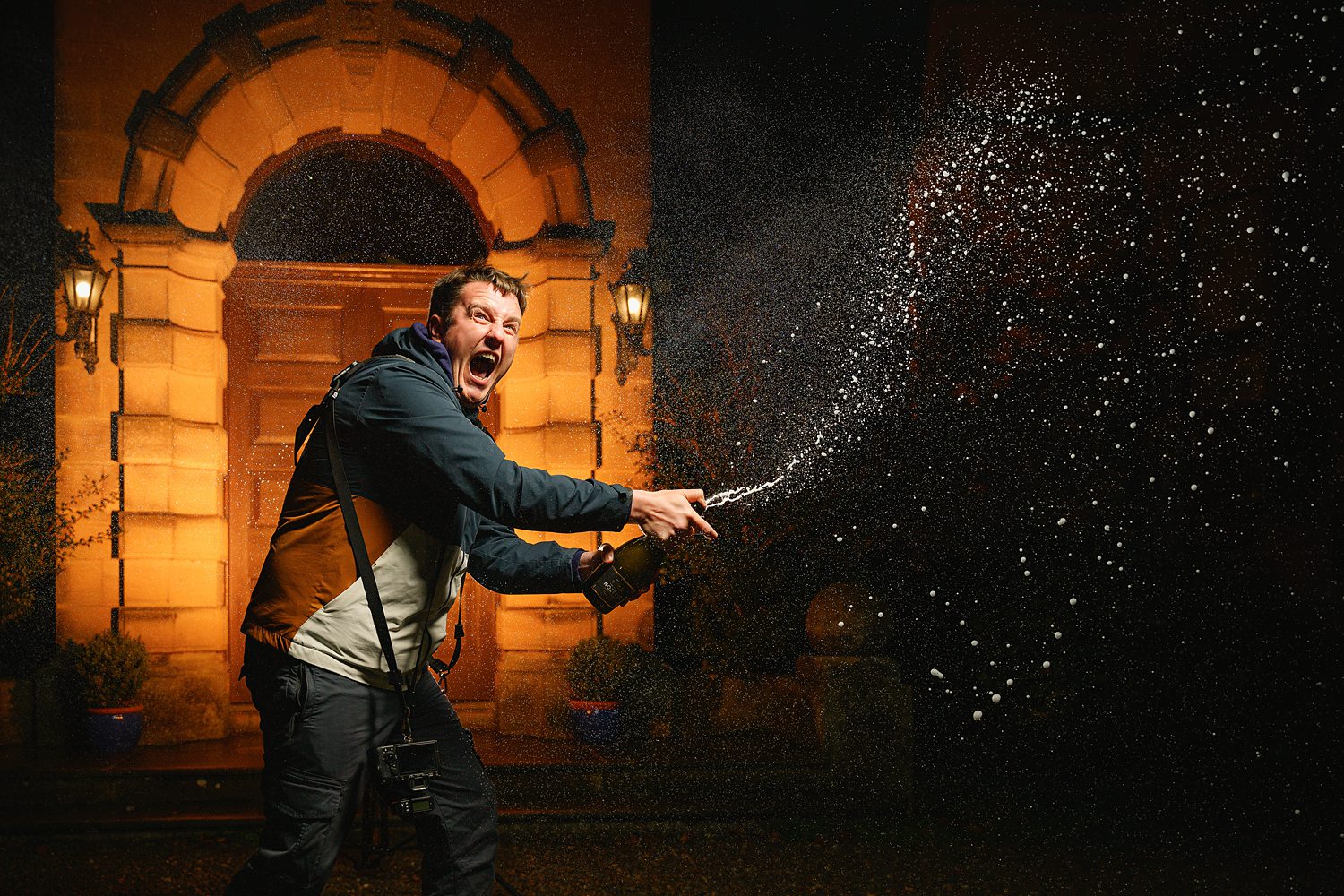 Man celebrating with champagne spray outside building