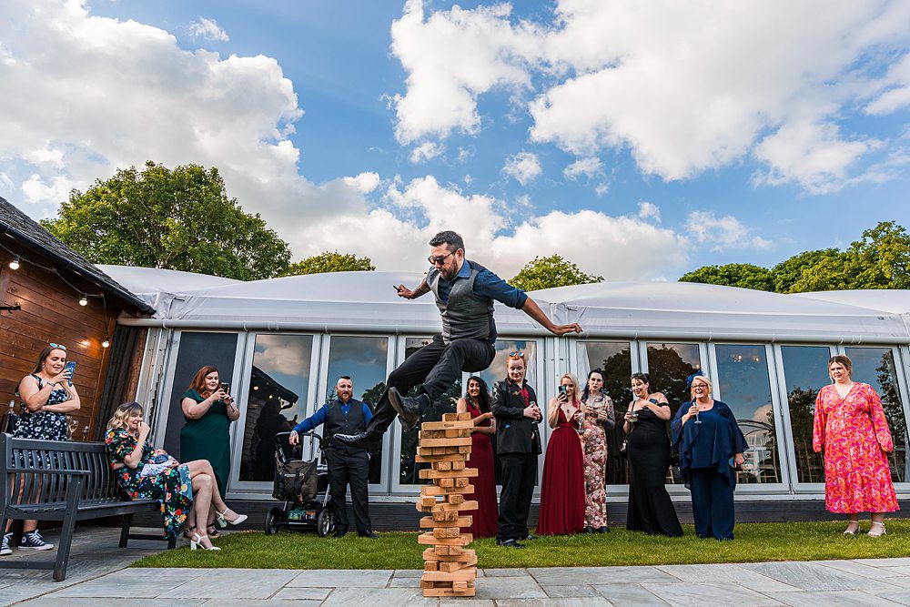Man balancing on giant Jenga at outdoor event.