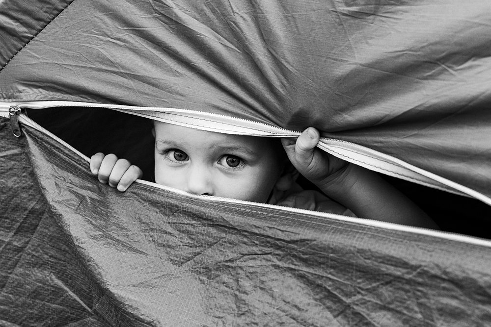 Child peeking through tent flap