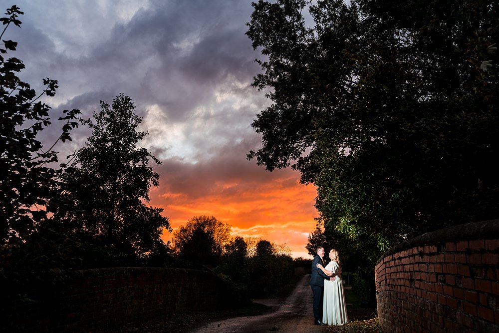 Couple embracing under vibrant sunset sky.
