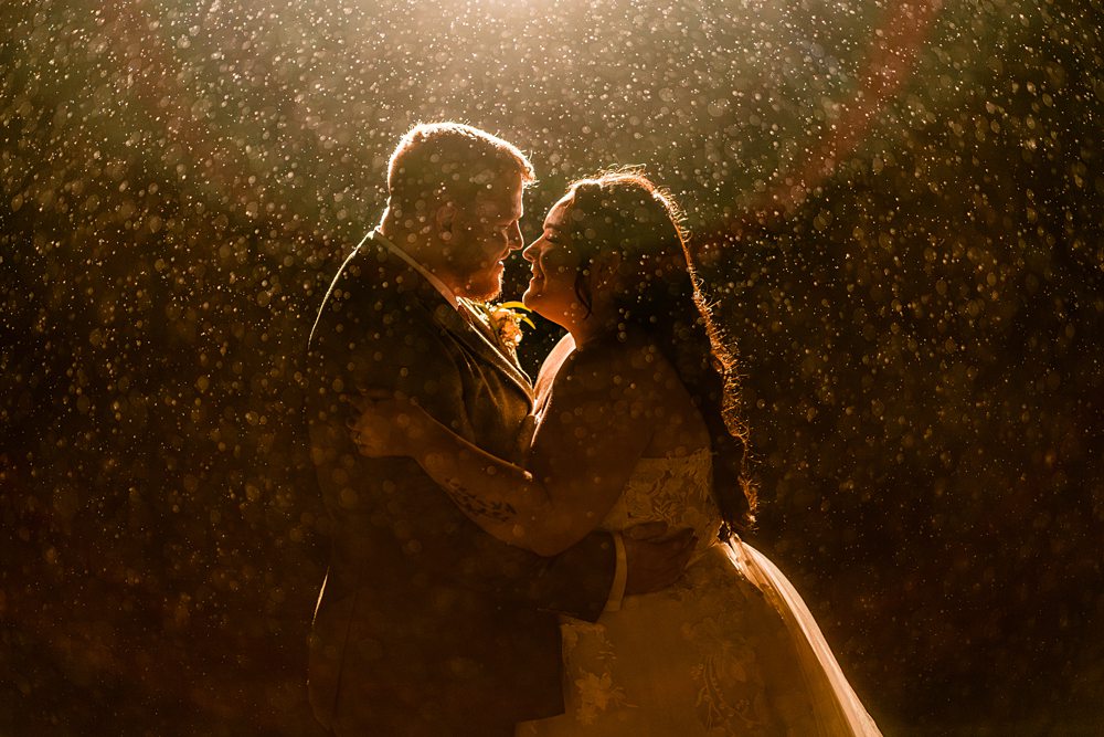 Romantic couple embraces under golden rain at night.