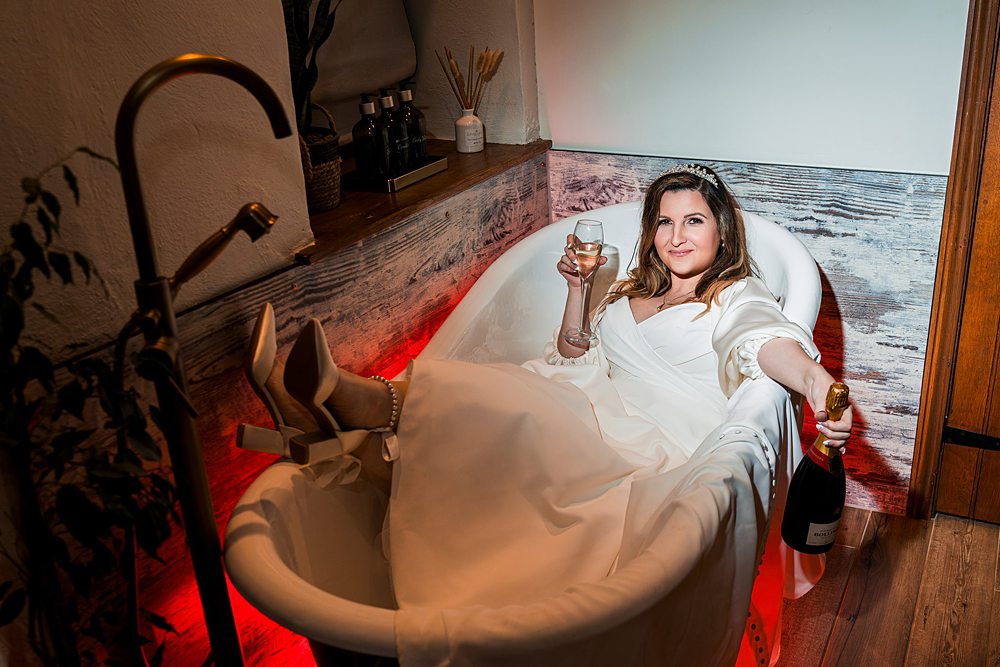 Bride relaxing with champagne in the bathtub.