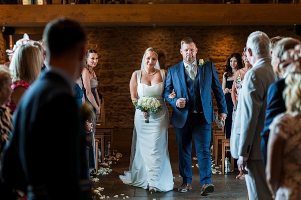 Bride walking down aisle with her father at wedding.