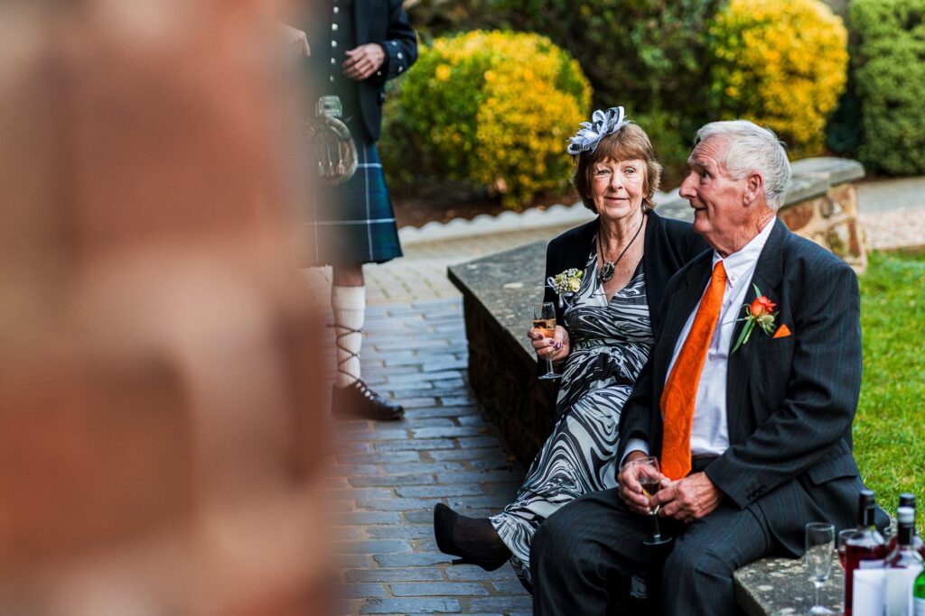 Elderly couple enjoying garden party with drinks.