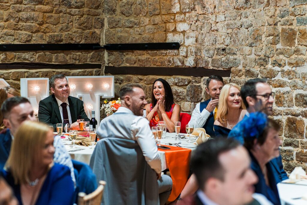 Guests smiling at a wedding reception in rustic venue.