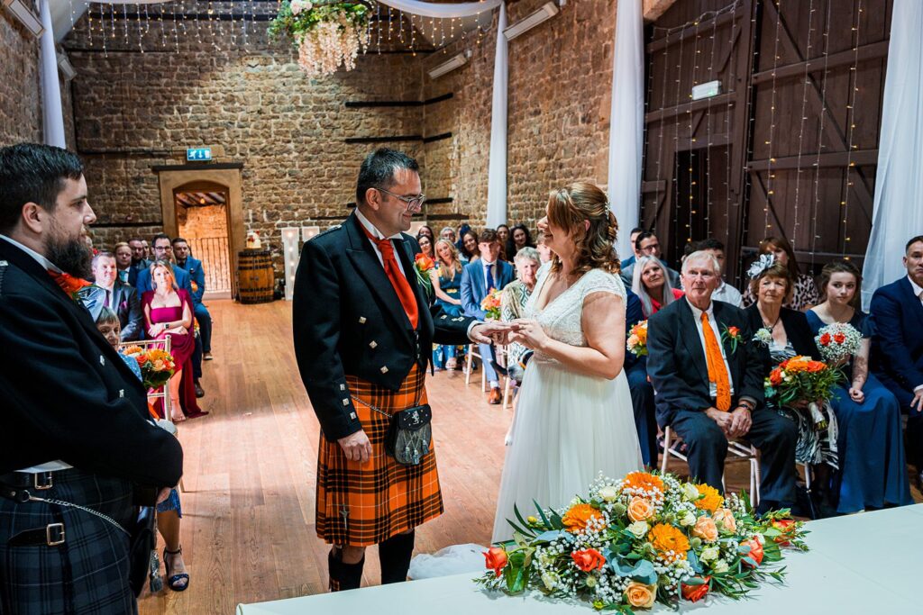 Couple exchanging rings at rustic wedding ceremony.