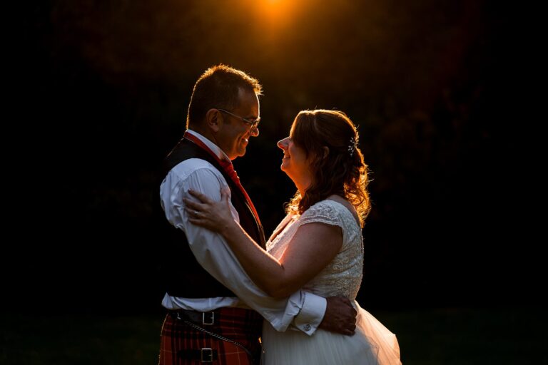 Couple embraces in warm sunset glow.