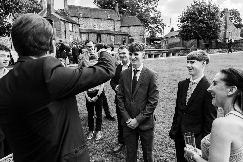 Guests smiling at outdoor event, historic building background.