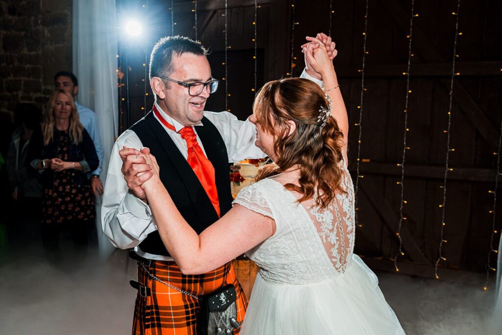 Couple dancing joyfully at wedding reception.