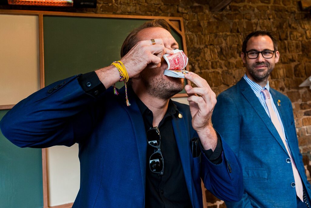 Man performing card trick in a blue suit.