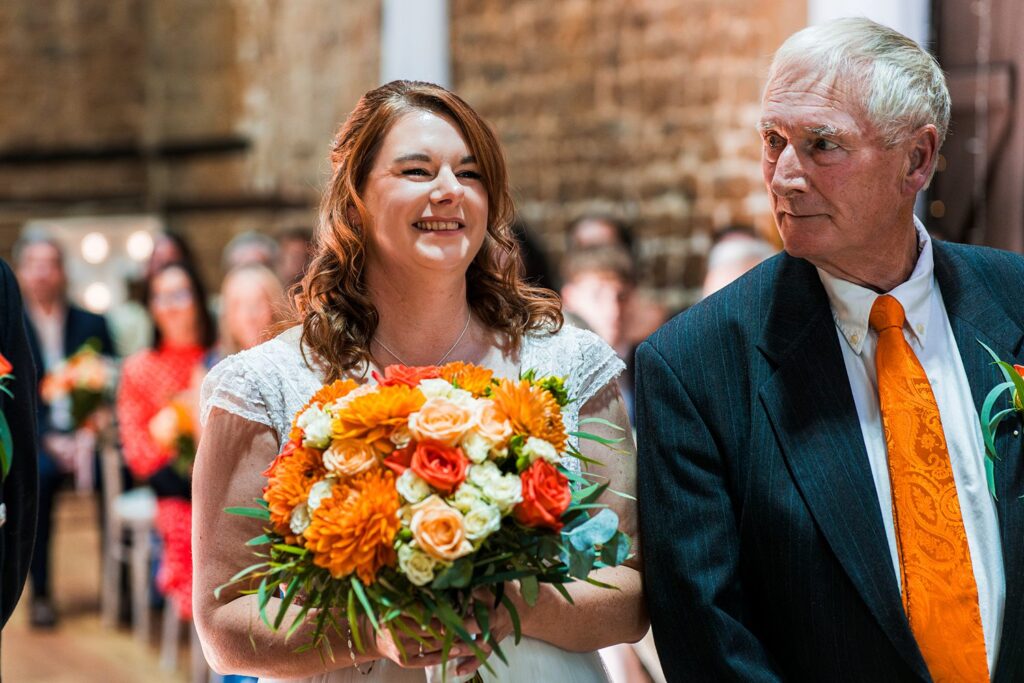 Bride smiling with bouquet and older gentleman.