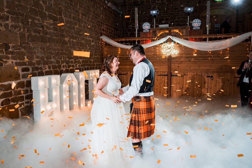 Couple dancing at wedding with fog and confetti.