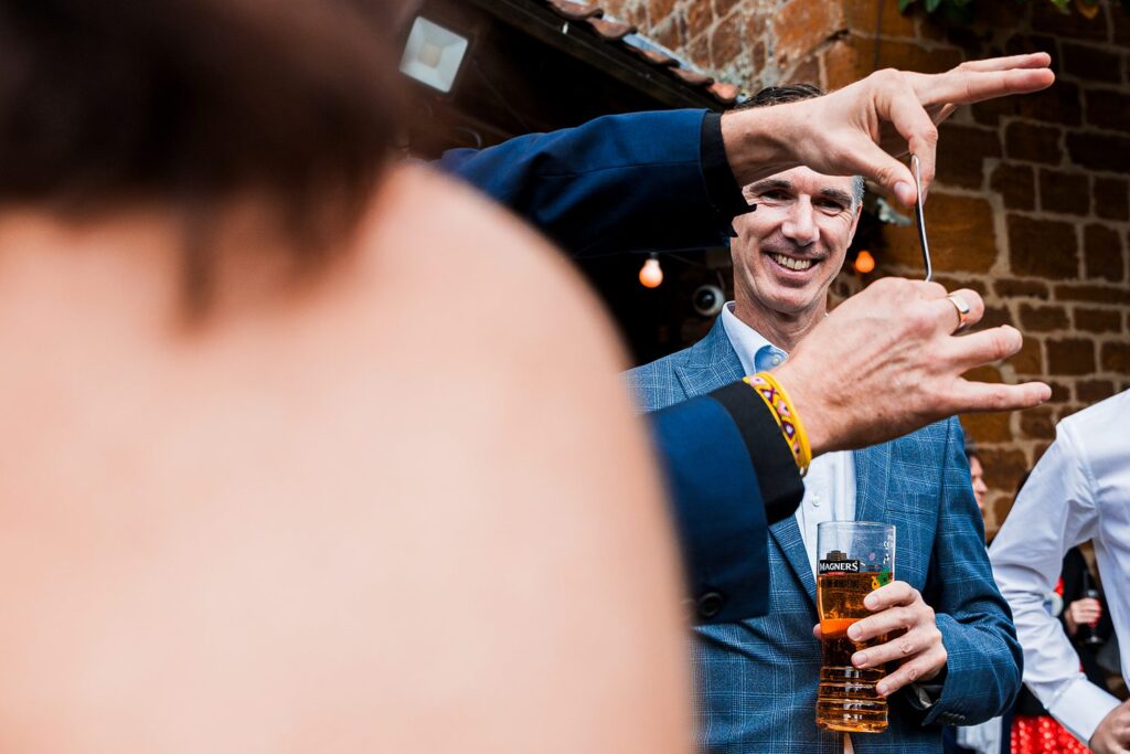 Man with drink watching spoon bending trick outdoors.