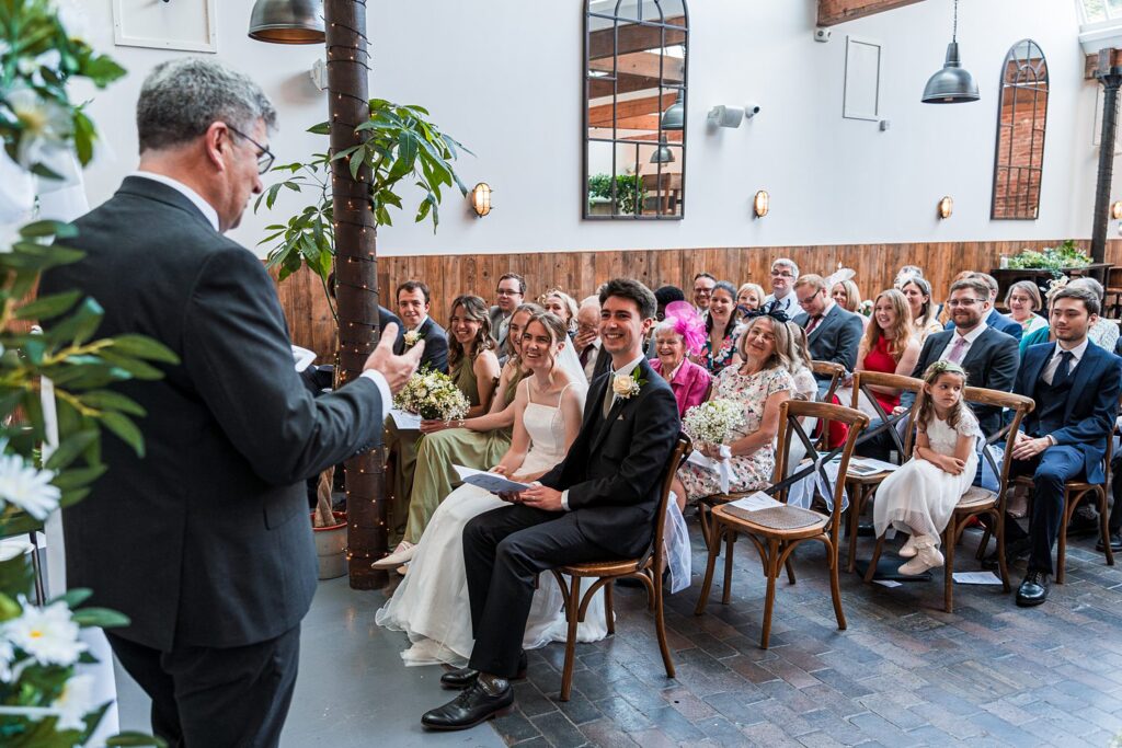 Indoor wedding ceremony with happy guests and couple.