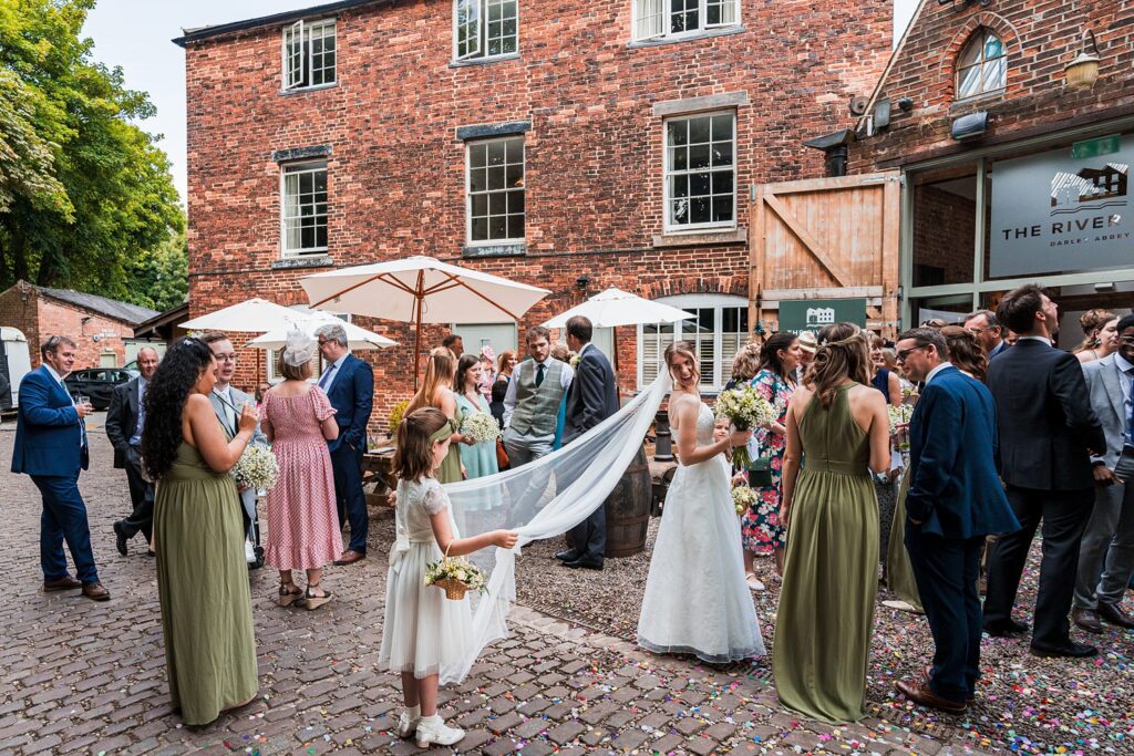 Outdoor wedding reception with bride and guests socialising.
