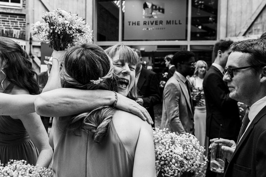Joyful wedding guests hugging at The River Mill.