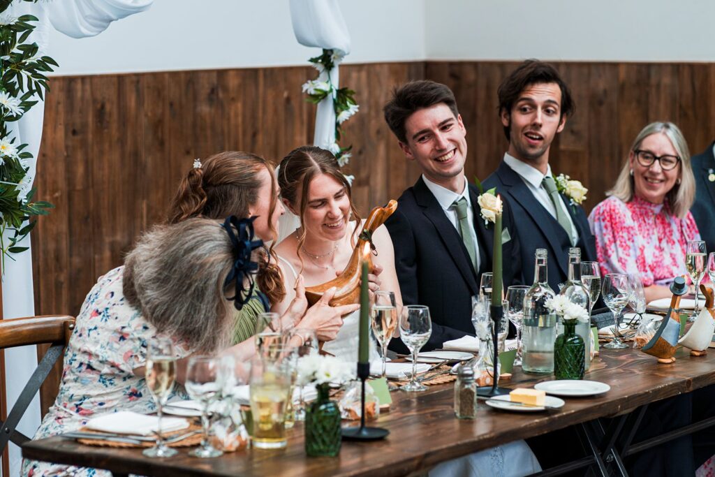 Wedding guests smiling and holding wooden duck gift.