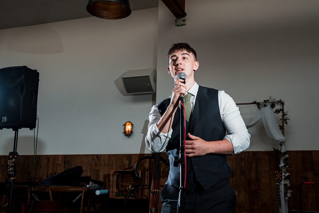 Man in suit singing into microphone at event.