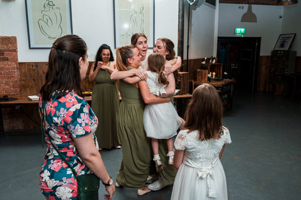 Group of women hugging at an indoor event.
