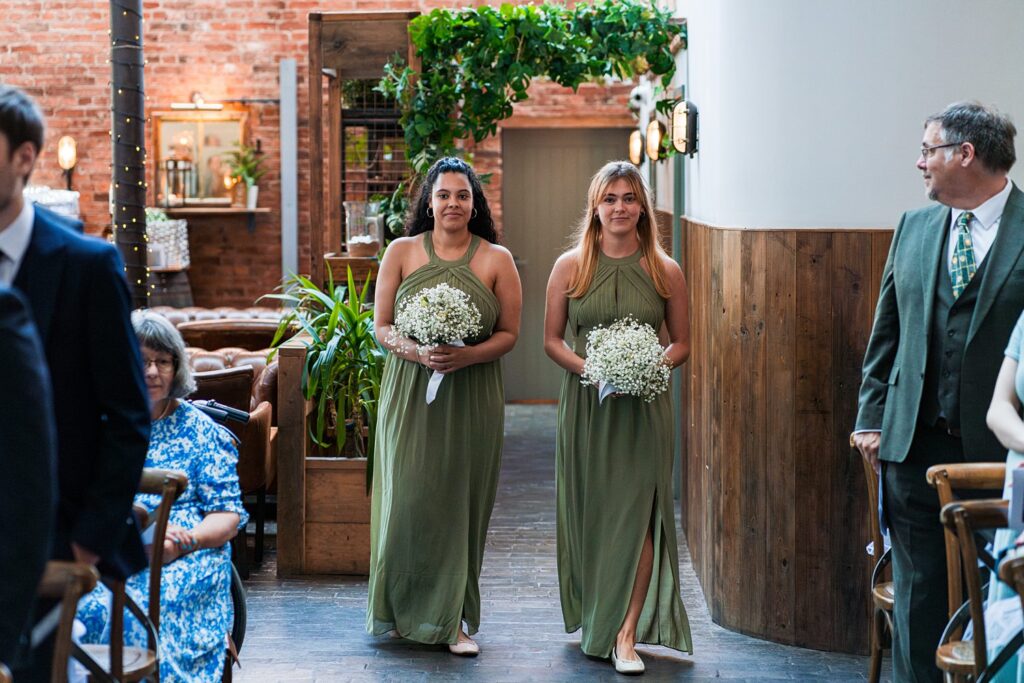Two bridesmaids in green dresses holding flowers