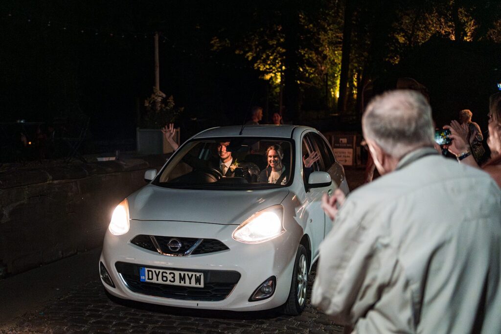 White car during night event with people photographing.