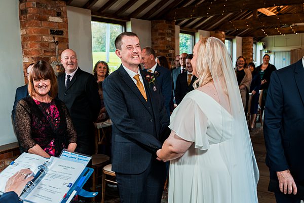 Couple exchanging vows at indoor wedding ceremony.