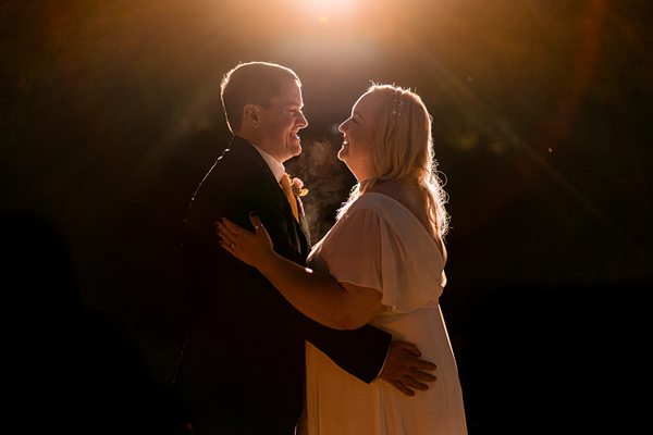 Couple dancing under warm spotlight at night.