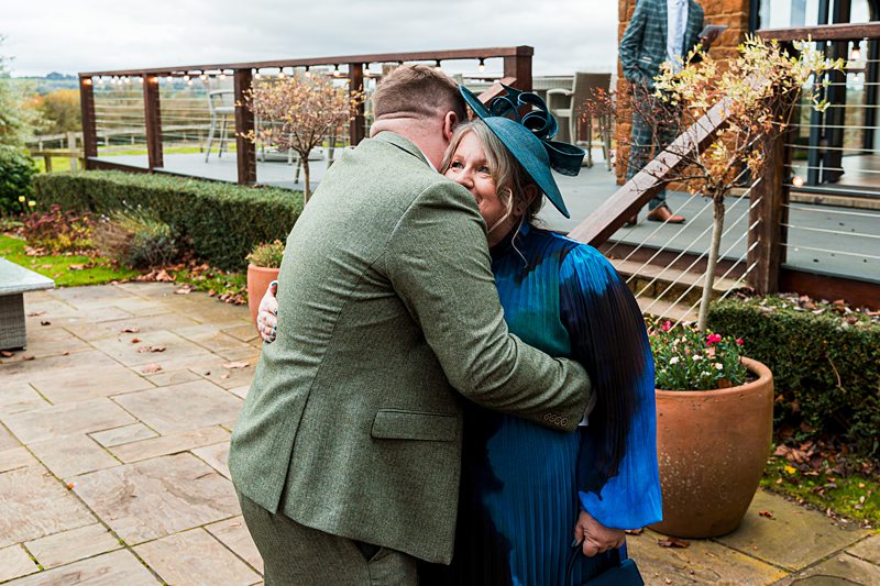 Two people embracing outdoors at a wedding venue.