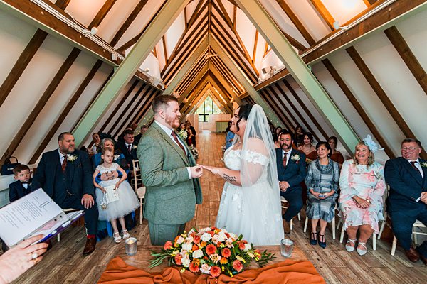 Bride and groom exchanging vows in rustic venue.