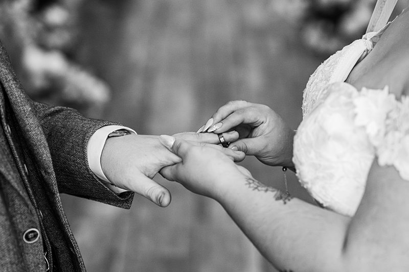 Bride placing ring on groom's finger during ceremony.