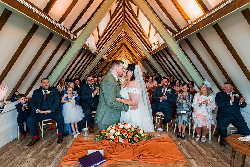 Bride and groom kiss at wedding ceremony.