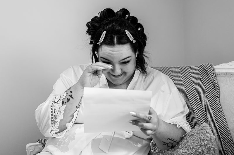Bride reading emotional letter, touching her eye.